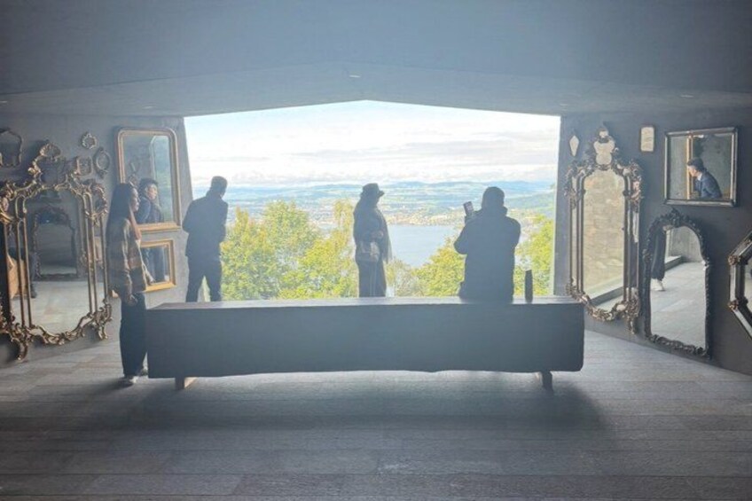 A bench overlooking a scenic view with people standing and taking photos. 3