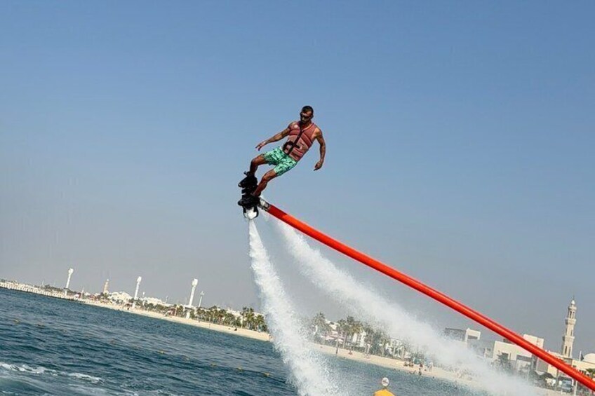 Una persona esegue un acrobazia in acqua su un jet ski, con uno skyline urbano sullo sfondo. 3