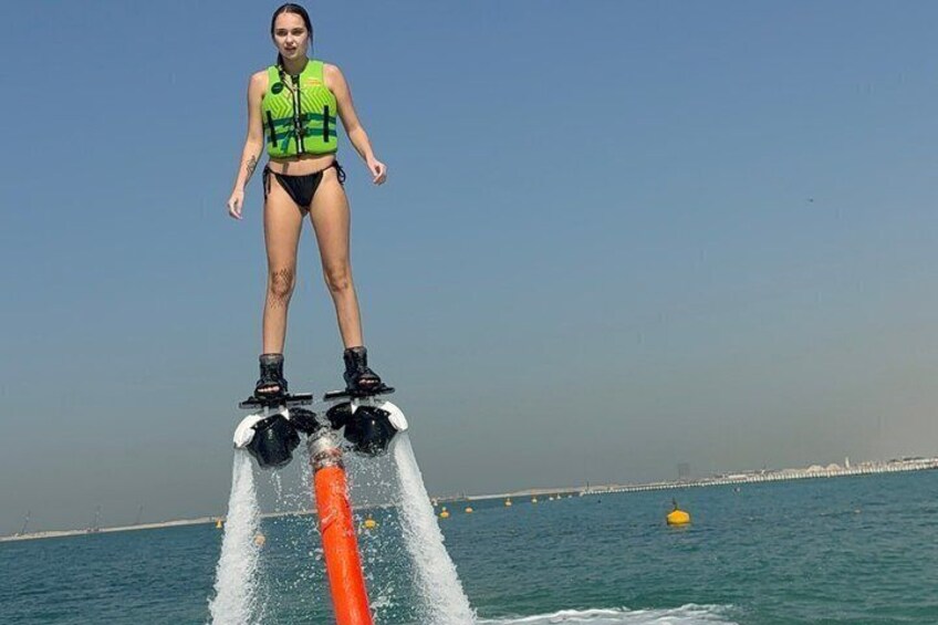 Una persona in piedi su un jet ski, indossa un giubbotto di salvataggio e stivali, mentre l'acqua schizza tutt'intorno. 4