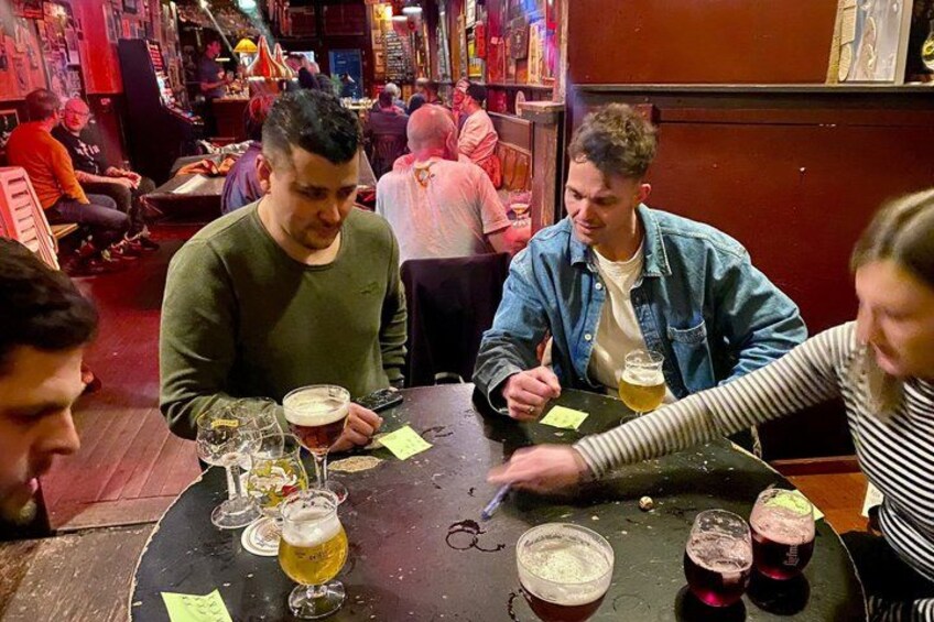 A group of people sitting at a table with multiple glasses of beer and sticky notes. 2