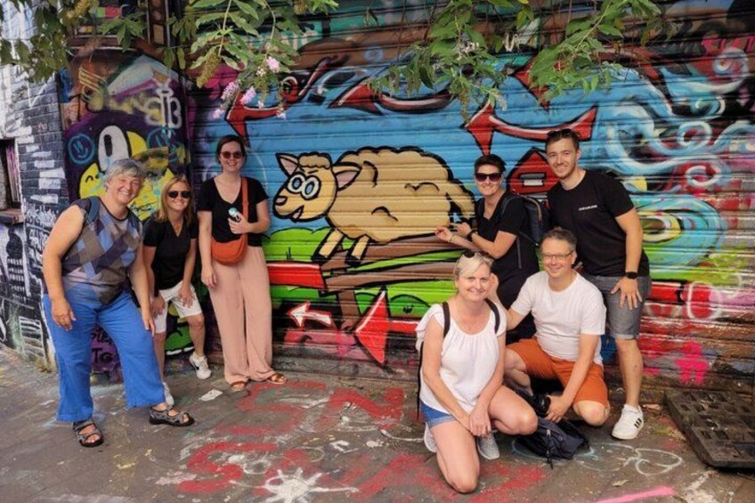 A group of people posing in front of a colorful graffiti wall with a cartoon character. 5
