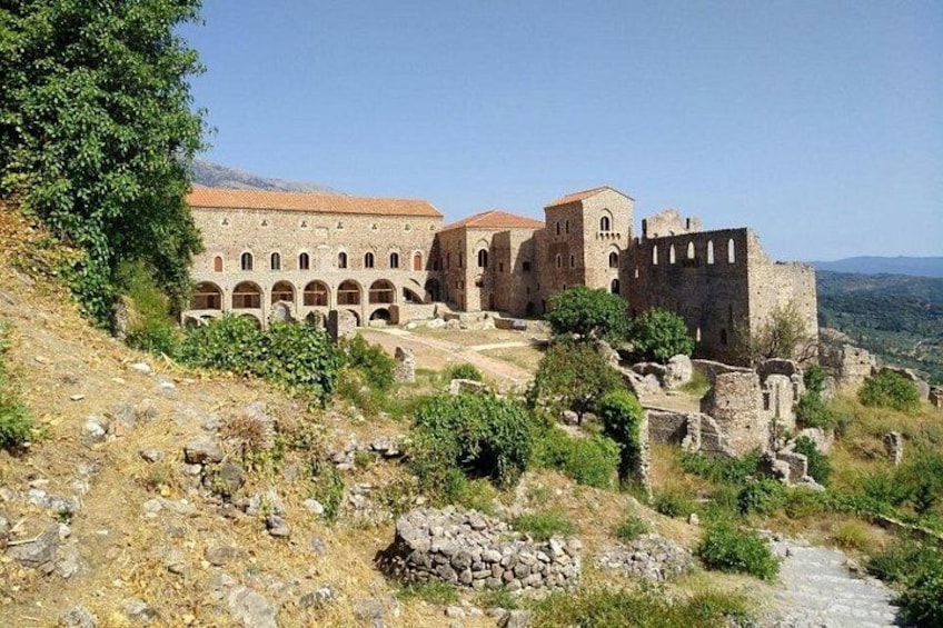 A historical building with arches, a castle-like structure, and ruins. 2