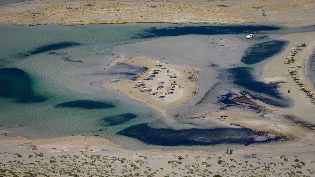 An aerial view of a coastal area with clear waters, a sandy beach, and a small cluster of buildings. 3