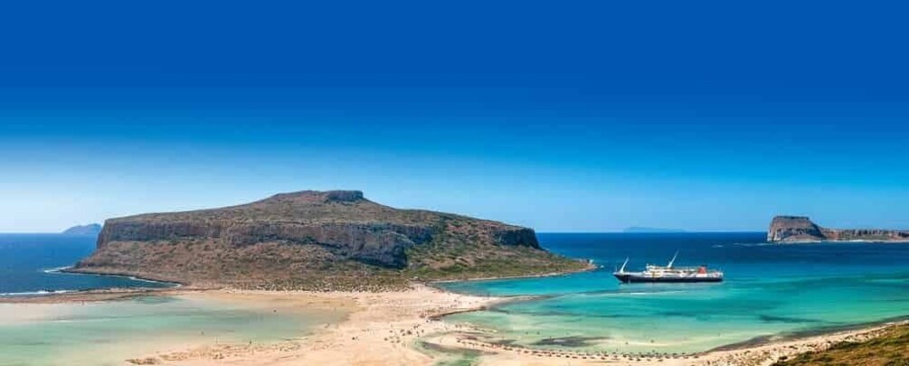 A coastal landscape with a large hill, a beach, and a ship in the water. 5
