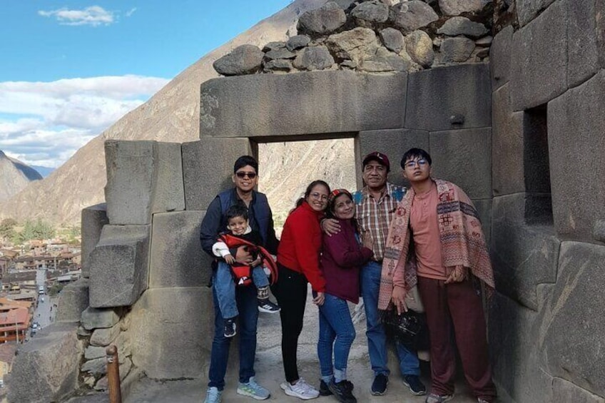 A group of people standing in front of a stone structure with a mountainous backdrop. 3