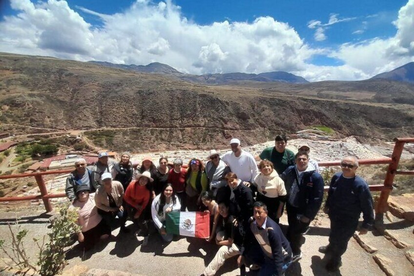 A group of people standing on a stone platform with a mountainous landscape in the background. 5