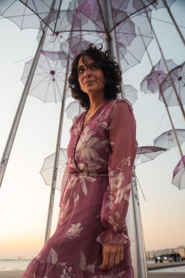 A person standing under a structure with multiple umbrellas, wearing a floral dress. 2