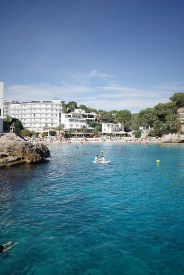 A coastal scene with clear blue water, a rocky shoreline, and buildings in the background. 4