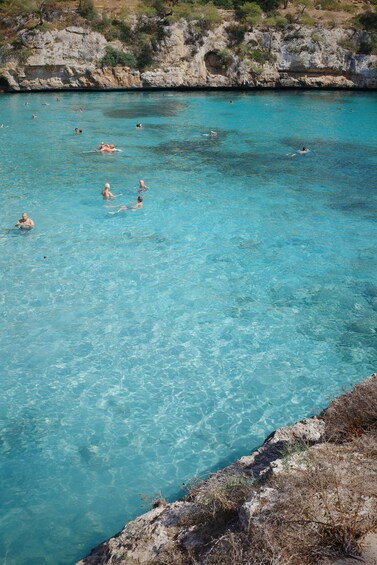 A clear turquoise sea with people swimming and floating. 5