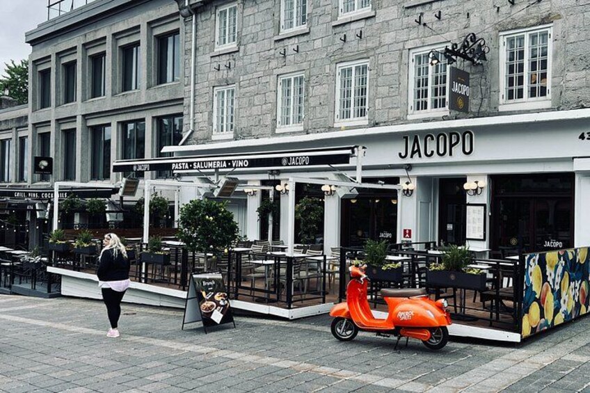 Una calle con un restaurante llamado 'Jacopo' y una scooter roja estacionada afuera. 4