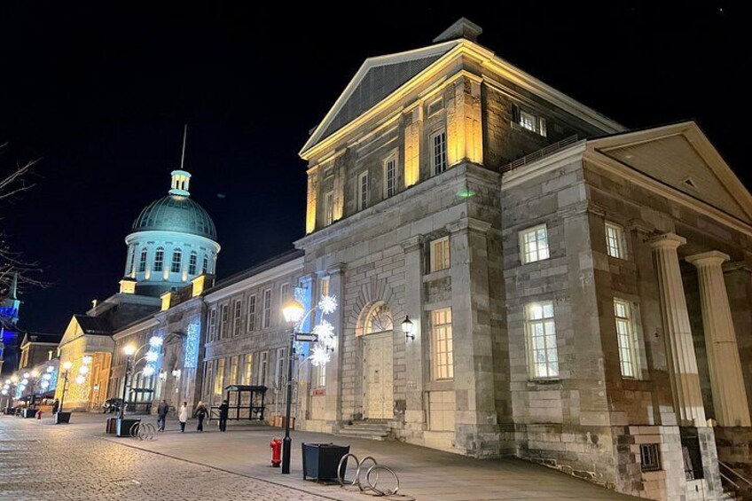 Un edificio histórico con una cúpula, iluminado por farolas, y una calle adoquinada. 2