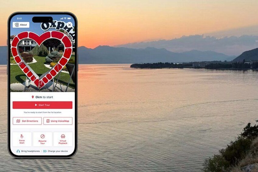 Ein Smartphone zeigt eine Reise-App mit einer malerischen Ansicht eines Sees und Bergen im Hintergrund. 1