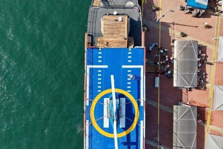 An aerial view of a boat deck with a blue floor, yellow markings, and a circular area in the center. 2