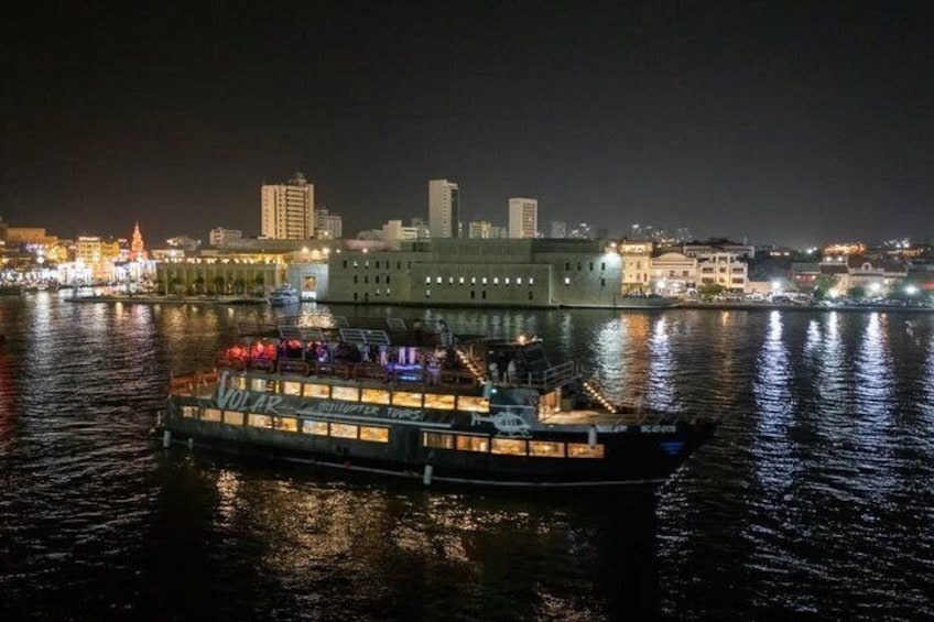 A riverboat with illuminated decks and a city skyline in the background. 5