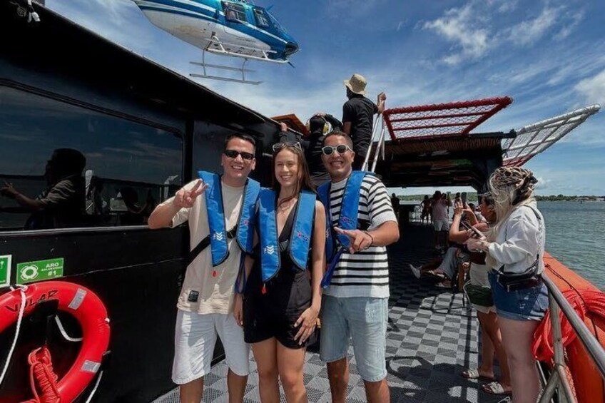 A group of people on a boat with life jackets, a helicopter in the background, and a lifebuoy on the side. 3