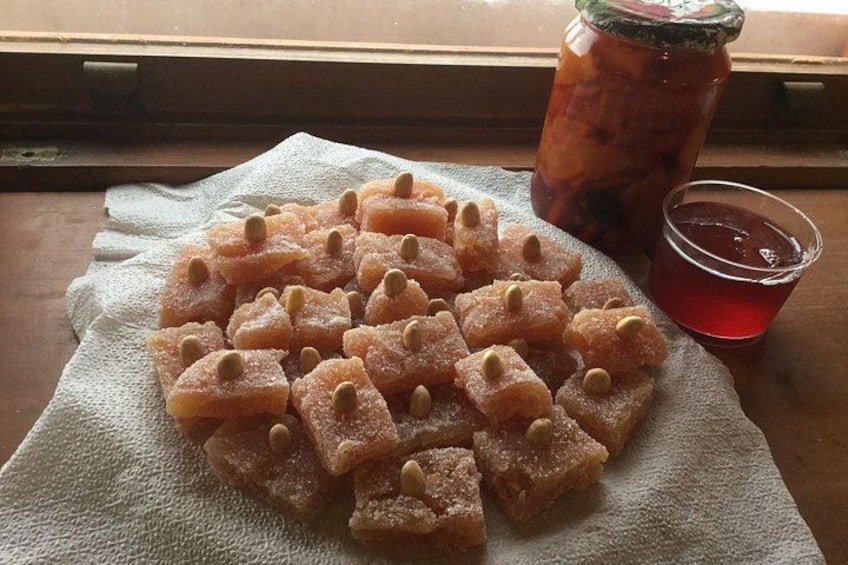 Une assiette contenant des petits gâteaux carrés, enrobés de sucre et parsemés de noix, posée sur une serviette en papier, un verre de thé glacé et un verre d’une boisson rouge. 3