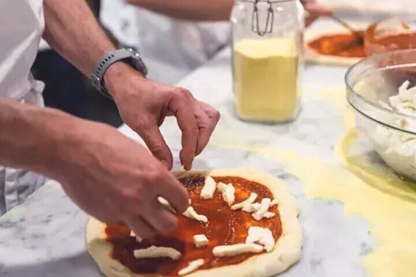 A person preparing pizza dough with tomato sauce and cheese. 4
