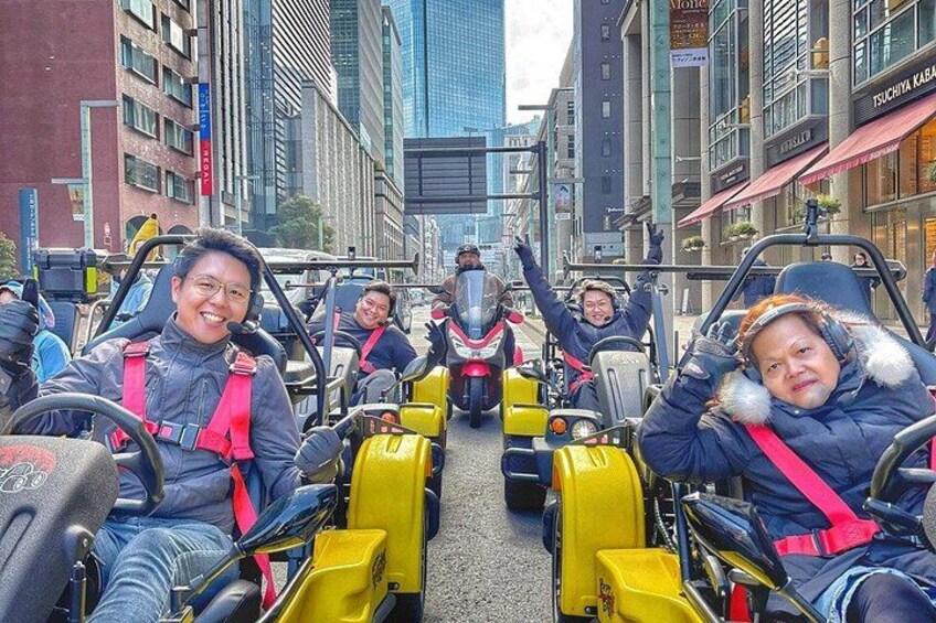 A group of people in yellow and black vehicles on a city street. 5