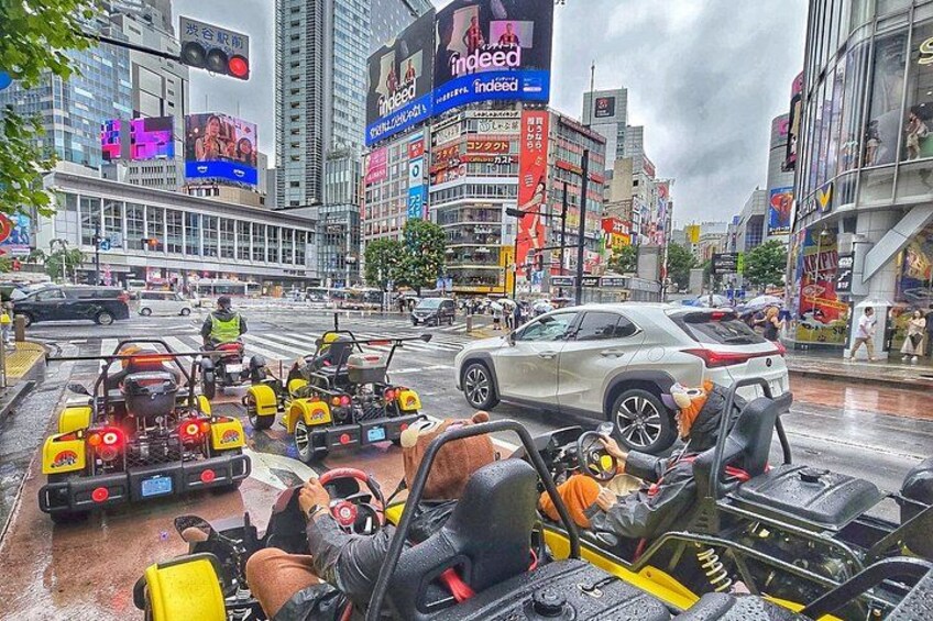 A busy urban street with yellow and red go-karts, a white car, and various billboards. 1