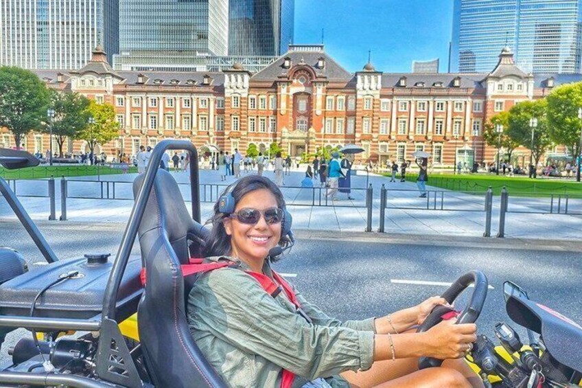 Una persona conduce un carrito de golf en un parque urbano con edificios históricos al fondo. 2