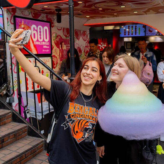 A person taking a selfie with a colorful cotton candy. 5
