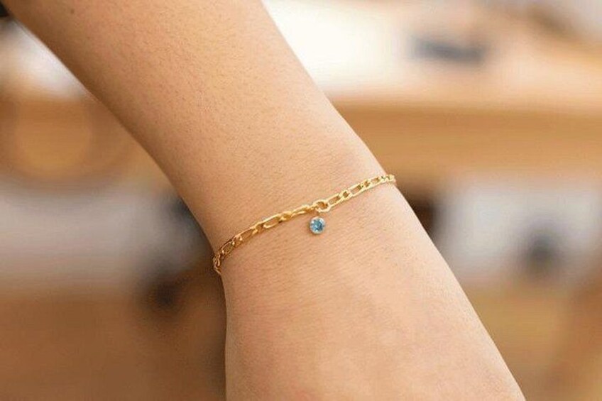 A gold bracelet with a blue gemstone on a wrist. 2