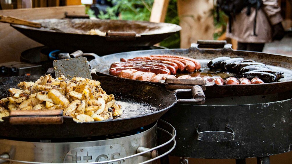 A variety of grilled foods including sausages, potatoes, and possibly fish on a grill. 2