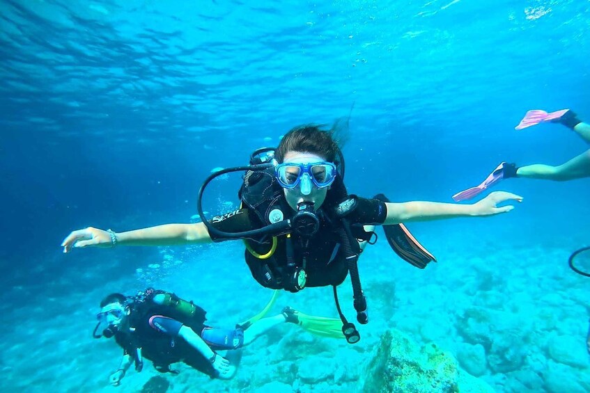A diver with a scuba tank and fins, swimming underwater. 1