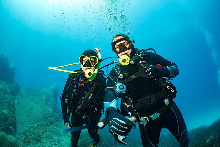 Two scuba divers underwater with fins and tanks. 3
