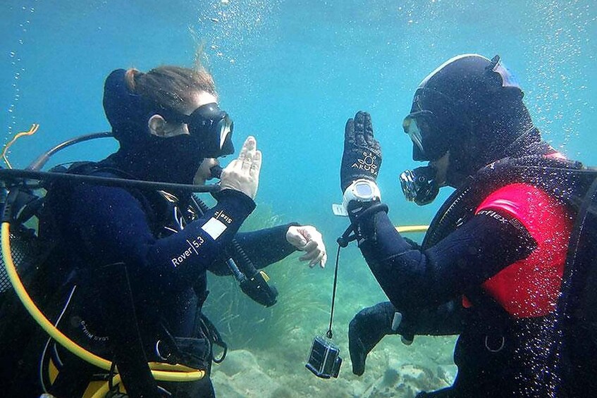 Two scuba divers underwater, one wearing a black wetsuit and the other in red, with scuba gear and a camera. 5