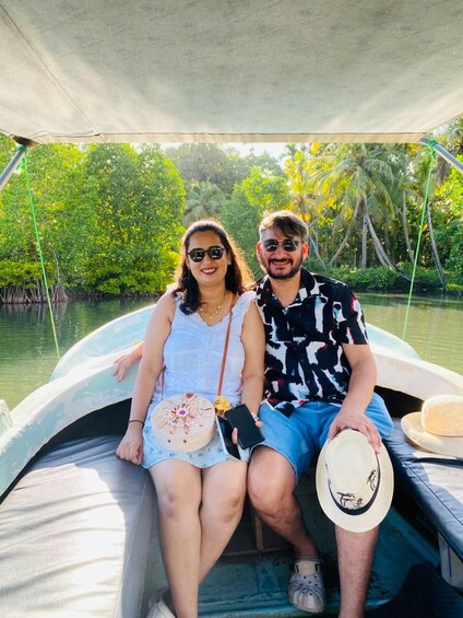Two people on a boat with a canopy, surrounded by water and greenery. 4