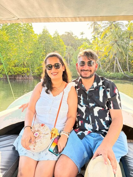 Two people on a boat in a mangrove area with water and greenery in the background. 3
