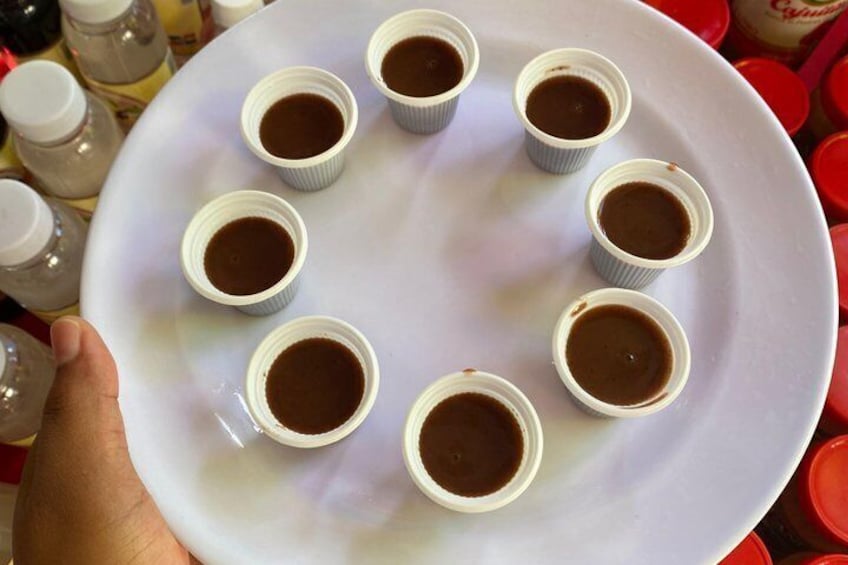 Un piatto bianco con otto piccole tazze di liquido scuro, probabilmente caffè o tè, disposte a cerchio. 3