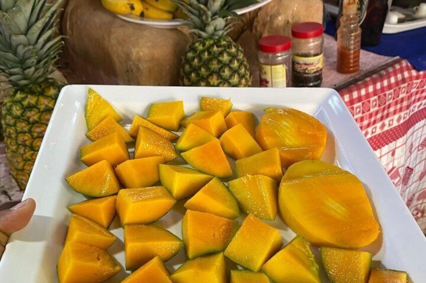 Un piatto bianco con cubetti di mango, un ananas e barattoli di spezie. 2