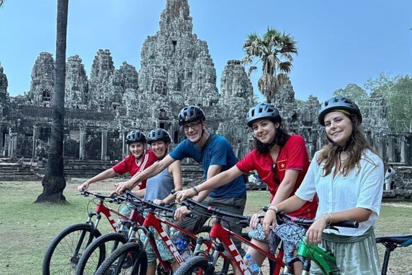 A group of people on bicycles in front of a large ancient temple. 1