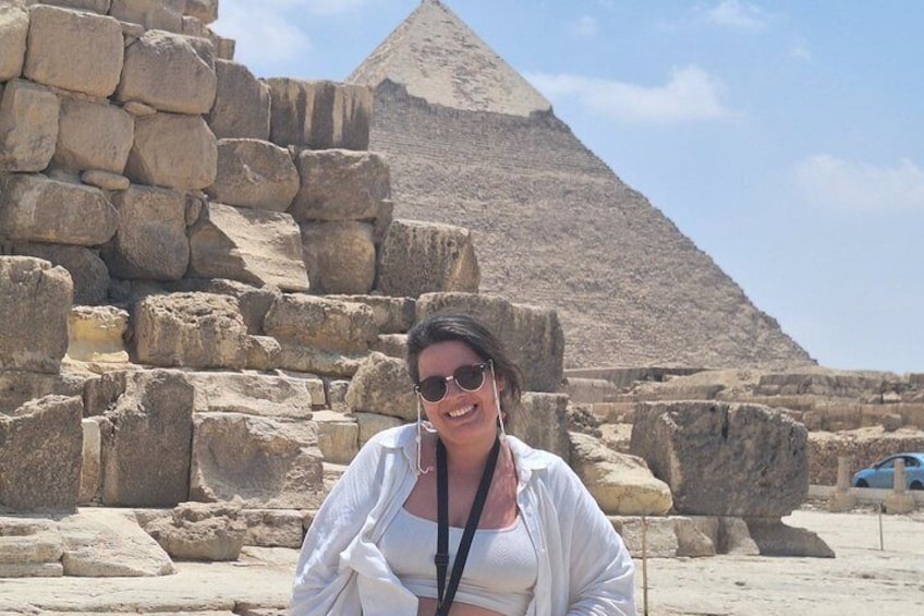 Een persoon voor oude Egyptische ruïnes, met een piramide op de achtergrond. 5