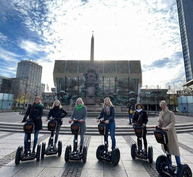 A group of people on Segway Hoverboards in an urban square with a monument in the background. 1