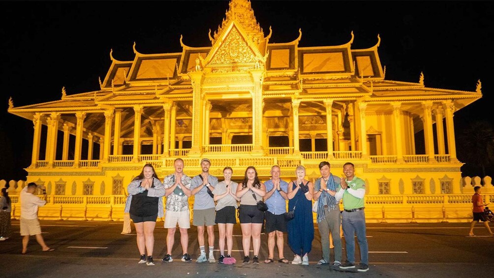 A group of people standing in front of a brightly lit temple with intricate architecture. 5