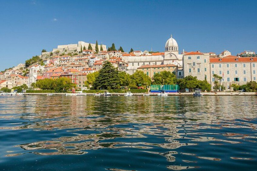 A coastal cityscape with historic buildings, a prominent dome structure, and a calm body of water reflecting the city. 5