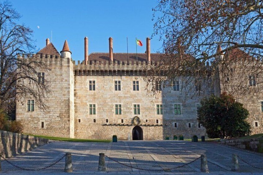 A historic stone castle with a central archway, flag, and a paved courtyard. 4