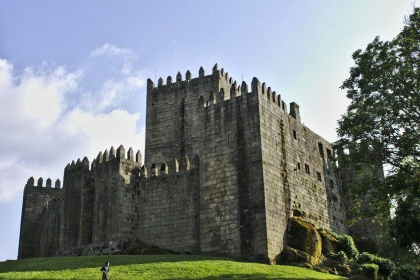 A large stone castle with multiple towers and a grassy foreground. 1