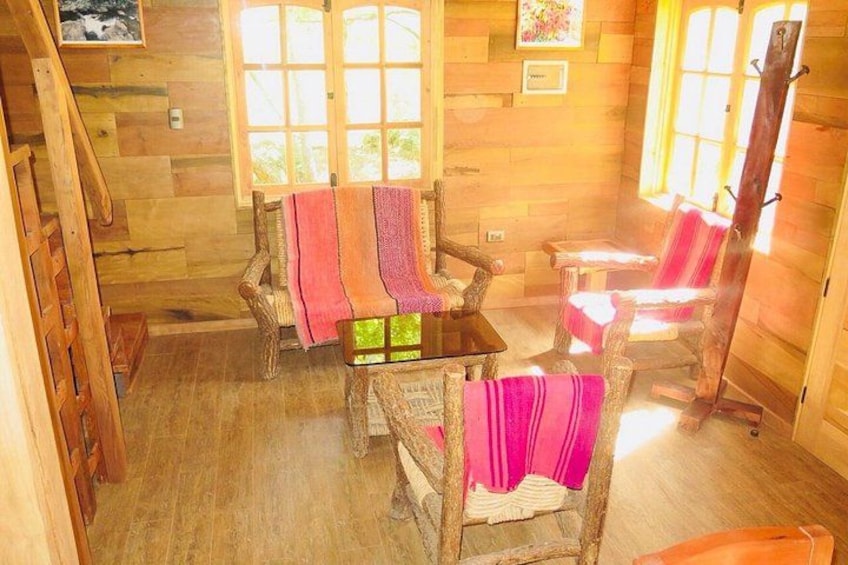 A wooden cabin interior with a staircase, wooden walls, a table, and chairs. 4