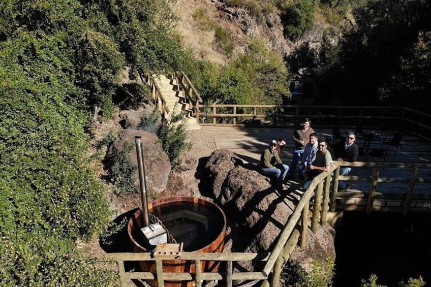 A hot spring area with wooden walkways and a stone basin. 3