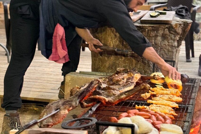 A person grilling various meats and sausages on an outdoor grill. 5
