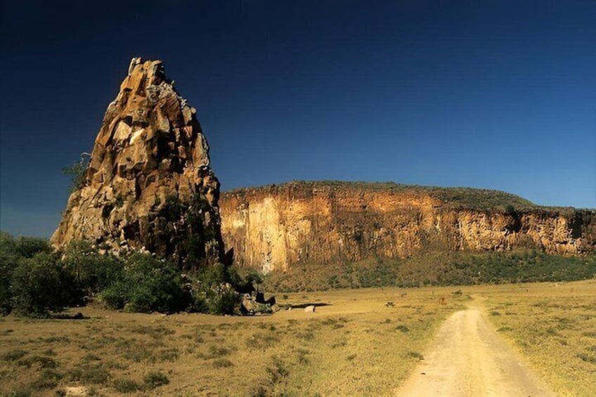 A rocky outcrop, a dirt path, and a cliff in a dry landscape. 1