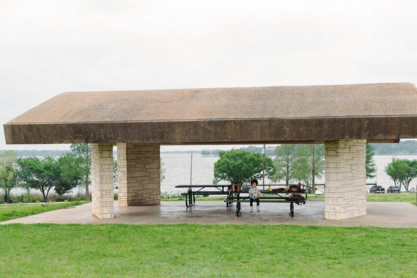 A large stone bench with a flat top, surrounded by a grassy area and a body of water in the background. 4