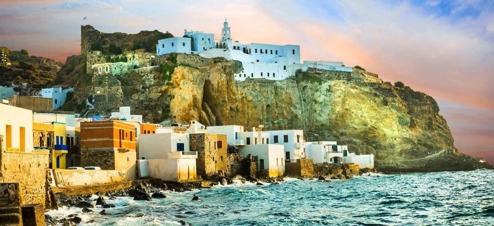 A coastal village with white buildings on a cliff, a lighthouse, and the sea. 1