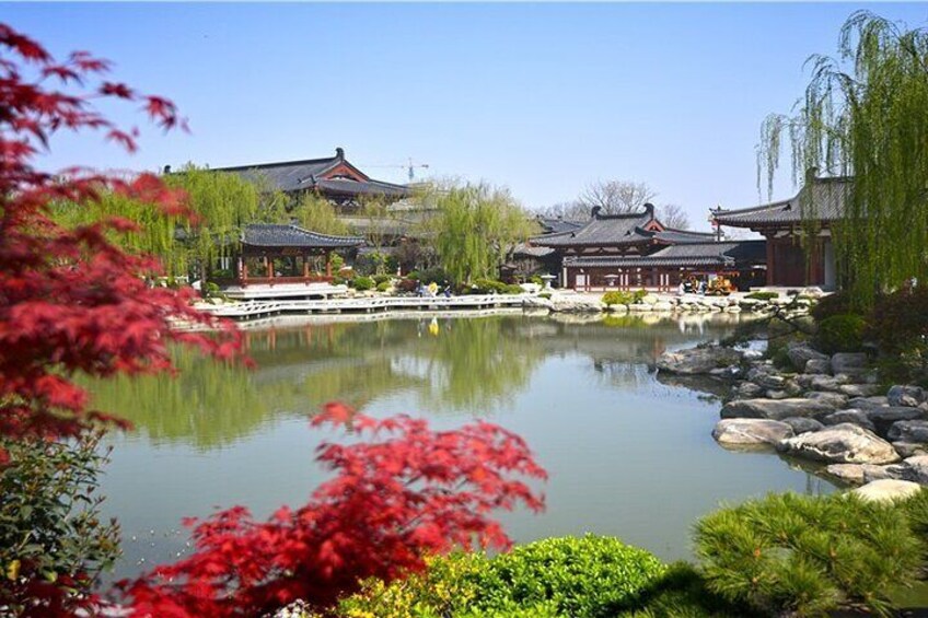 A traditional building with a pond, surrounded by rocks and foliage. 2