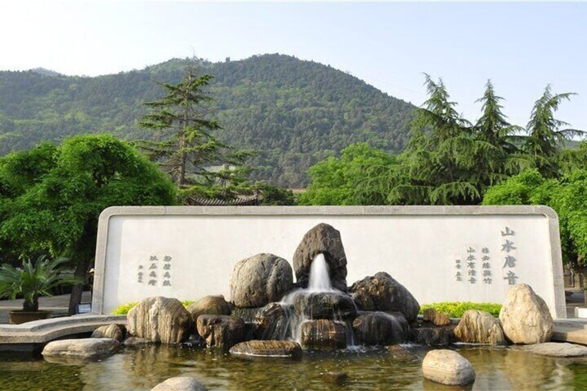 A rock garden with a waterfall, surrounded by trees and a mountain in the background. 4