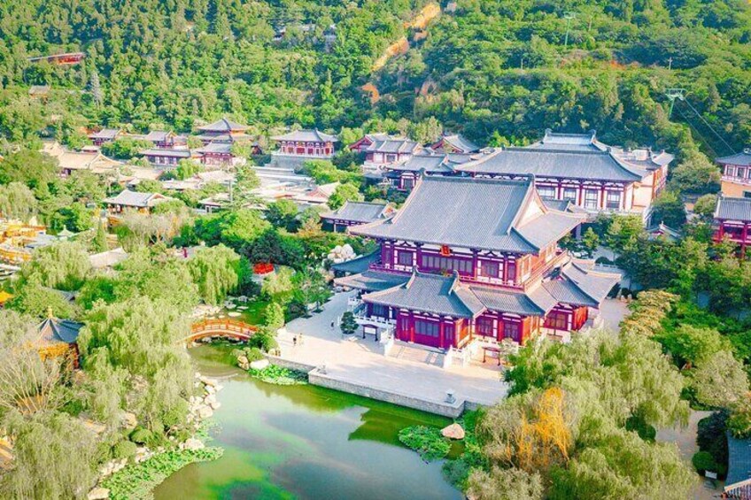 A traditional Chinese village with red buildings, a river, and surrounding greenery. 1